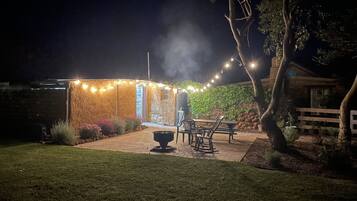 A stone building with string lights, a fire pit, and outdoor seating.