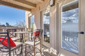 Ein überdachter Patio-Bereich mit Tisch und Stühlen, eine Schiebetür und Blick auf die umliegende Landschaft.