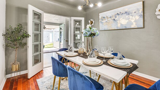 A dining area with a white table set for four, blue chairs, and a large abstract painting on the wall. - Bar & Fire Pit: Pet-Friendly Phoenix 'La Casita' (Phoenix)