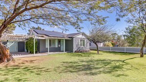 A house with a covered porch, a solar panel roof, and a well-maintained lawn. - Bar & Fire Pit: Pet-Friendly Phoenix 'La Casita' (Phoenix)