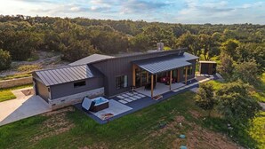 A modern house with a patio, a hot tub, and a covered outdoor seating area. - Outbound Ranch, Hot tub, Sauna, Fireplace, Views! (fredericksburg)