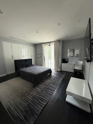 A modern bedroom with a bed, wardrobe, bedside table, mirror, and a large window with curtains. - Spacious Beautiful Modern Home in Sherman Oaks! (Los Angeles)