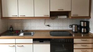A kitchen with white cabinets, a dishwasher, a coffee maker, and a kettle. - Apartment 'Business' with Sea View, Balcony and Wi-Fi (Weiden in der Oberpfalz)