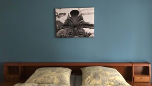 A bed with floral bedding, a wooden headboard, and a wall-mounted artwork. - Apartment 'Business' with Sea View, Balcony and Wi-Fi (Weiden in der Oberpfalz)