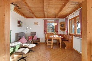 A wooden interior with a dining table, chairs, a bench, and a radiator.