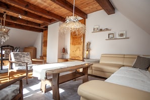 Une pièce chaleureuse avec un plafond en bois, un canapé, une table et des chaises.