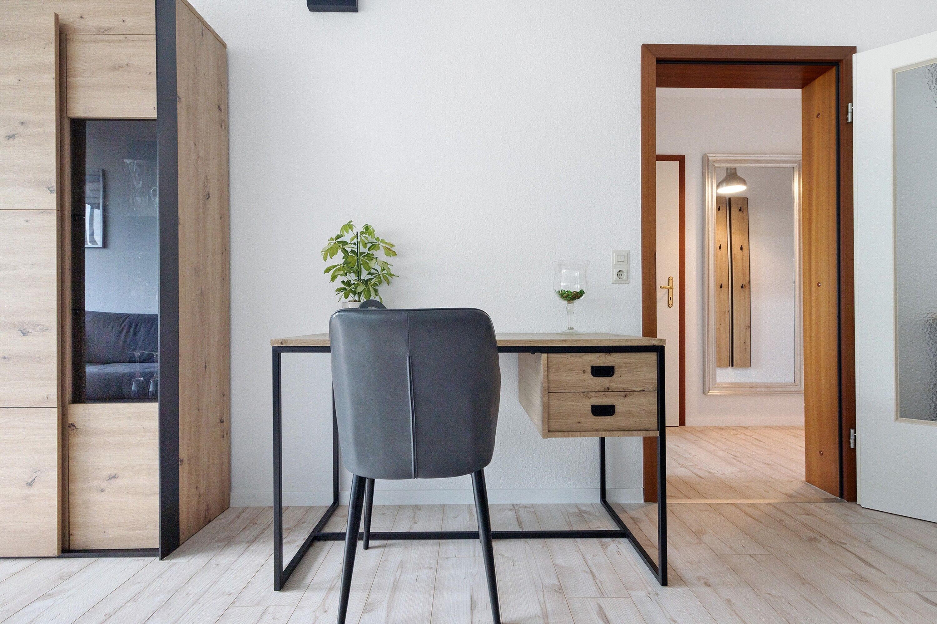 A modern room with a desk, chair, and a plant.