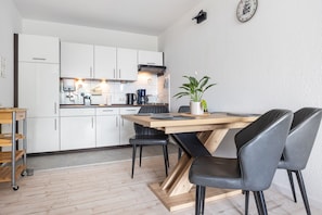 A modern kitchen with white cabinets, a wooden dining table, and black chairs.