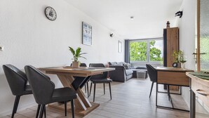 A modern dining area with a wooden table and chairs, a sofa, and a view of the outdoors.