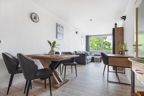 A modern dining area with a wooden table and chairs, a sofa, and a view of the outdoors.