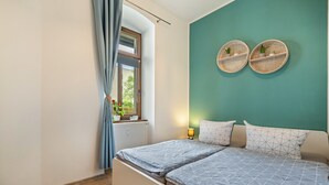 Ein Schlafzimmer mit Bett, einem Fenster mit Vorhängen, einem Heizkörper und Wanddekoration.