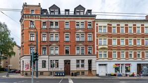 Ein mehrgeschossiges Gebäude im klassischen Stil, mit einem zentralen Eingang, der eine Tür und Fenster im Erdgeschoss aufweist.