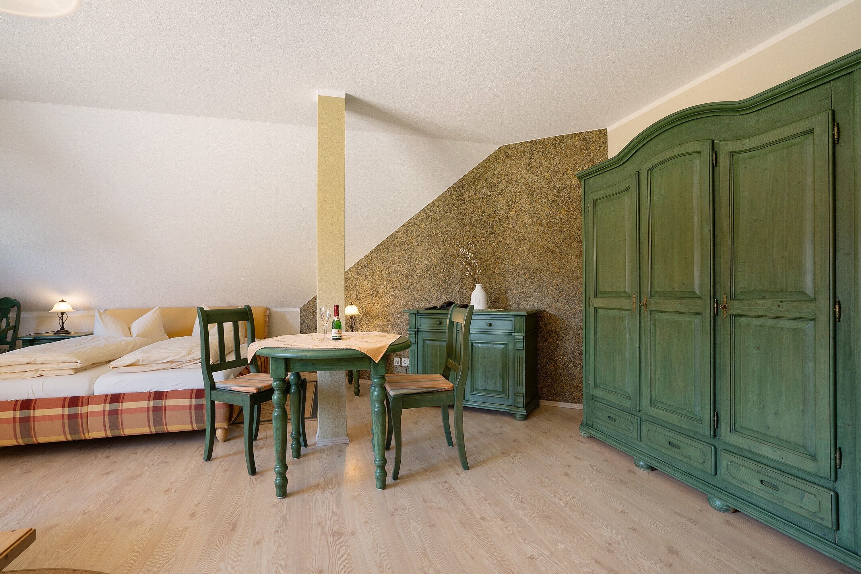 Ein Schlafzimmer mit einem Bett, zwei Stühlen, einem Tisch, einer Kommode und einer Treppe.