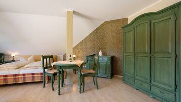 Ein Schlafzimmer mit einem Bett, zwei Stühlen, einem Tisch, einer Kommode und einer Treppe.
