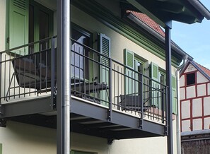 Ein Balkon mit Metallgeländern, einer grünen Tür und einem roten Dach.