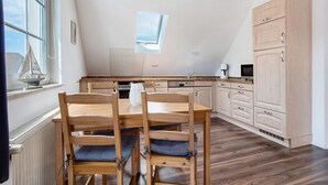 A kitchen with wooden furniture, a window, and a view of the sky. - Apartment 'Fewo 1' with Balcony and Wi-Fi (Koserow)