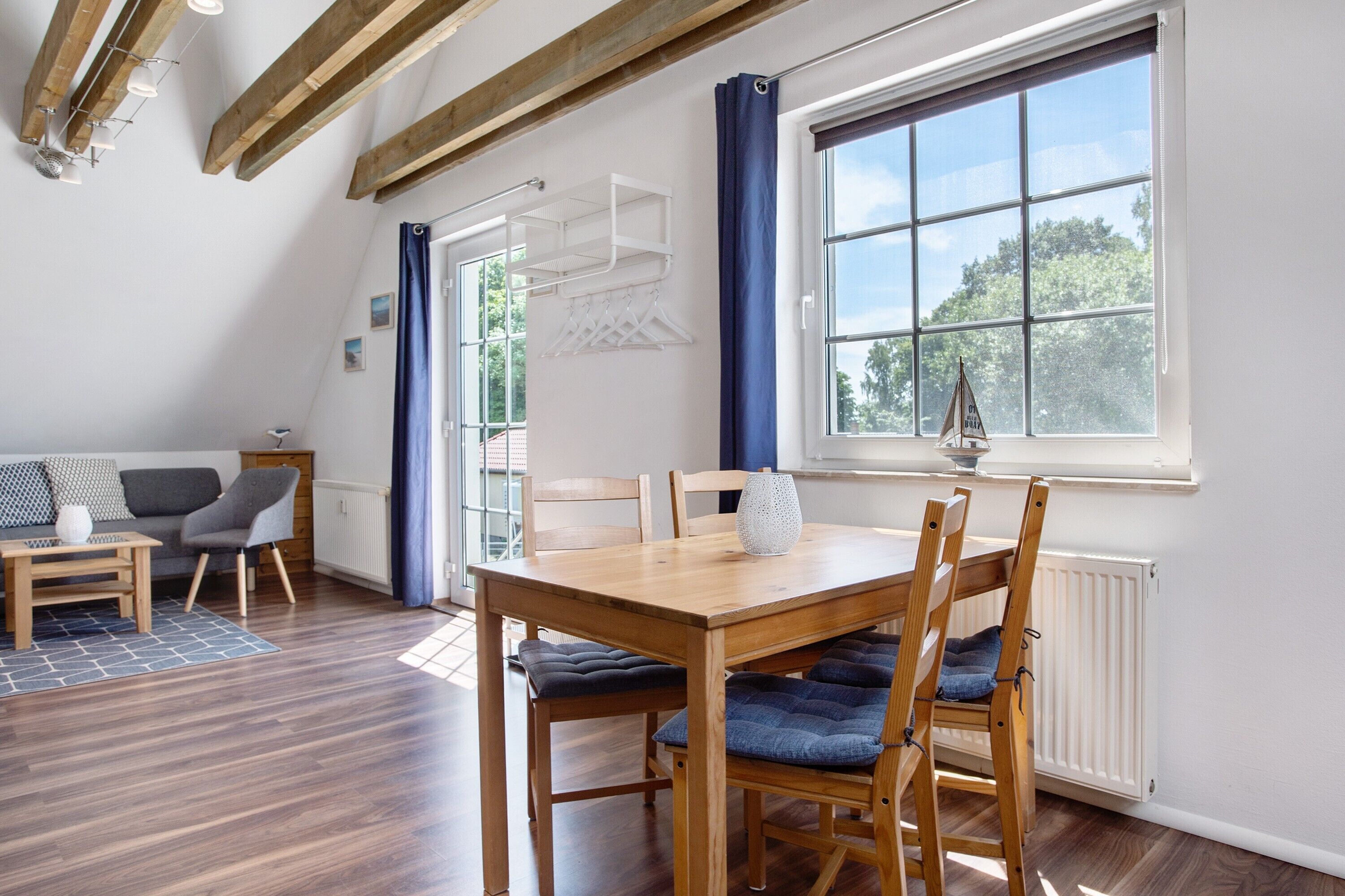 A dining area with a wooden table and chairs, a window with a view, and a blue curtain.