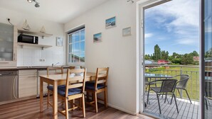 A modern kitchen with wooden cabinets, a microwave, and a dining area with a table and chairs. - Apartment 'Fewo 2' with Balcony and Wi-Fi (Koserow)