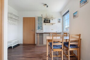 A compact kitchen with a microwave, wooden cabinets, and a dining area with chairs.