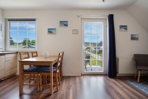 A room with a dining table, chairs, a radiator, and a view through a door.