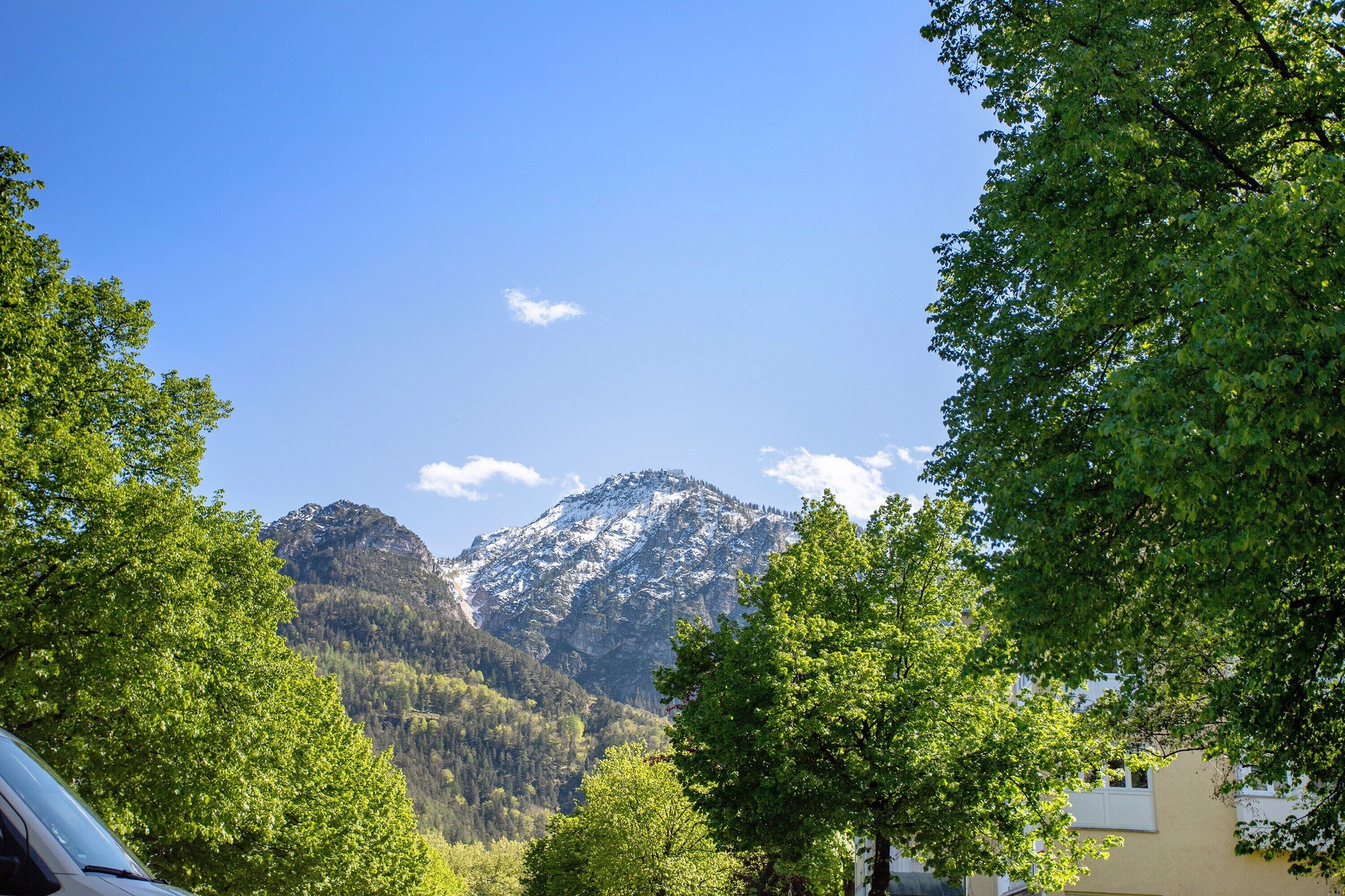 A mountain landscape with a clear sky, surrounded by trees and a building.