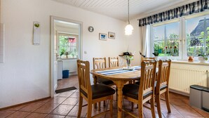 Un comedor con una mesa y sillas de madera, una lámpara colgante, un ventanal con vistas y un radiador.