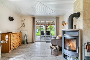 A cozy living room with a fireplace, wooden furniture, and a view to the outdoors.