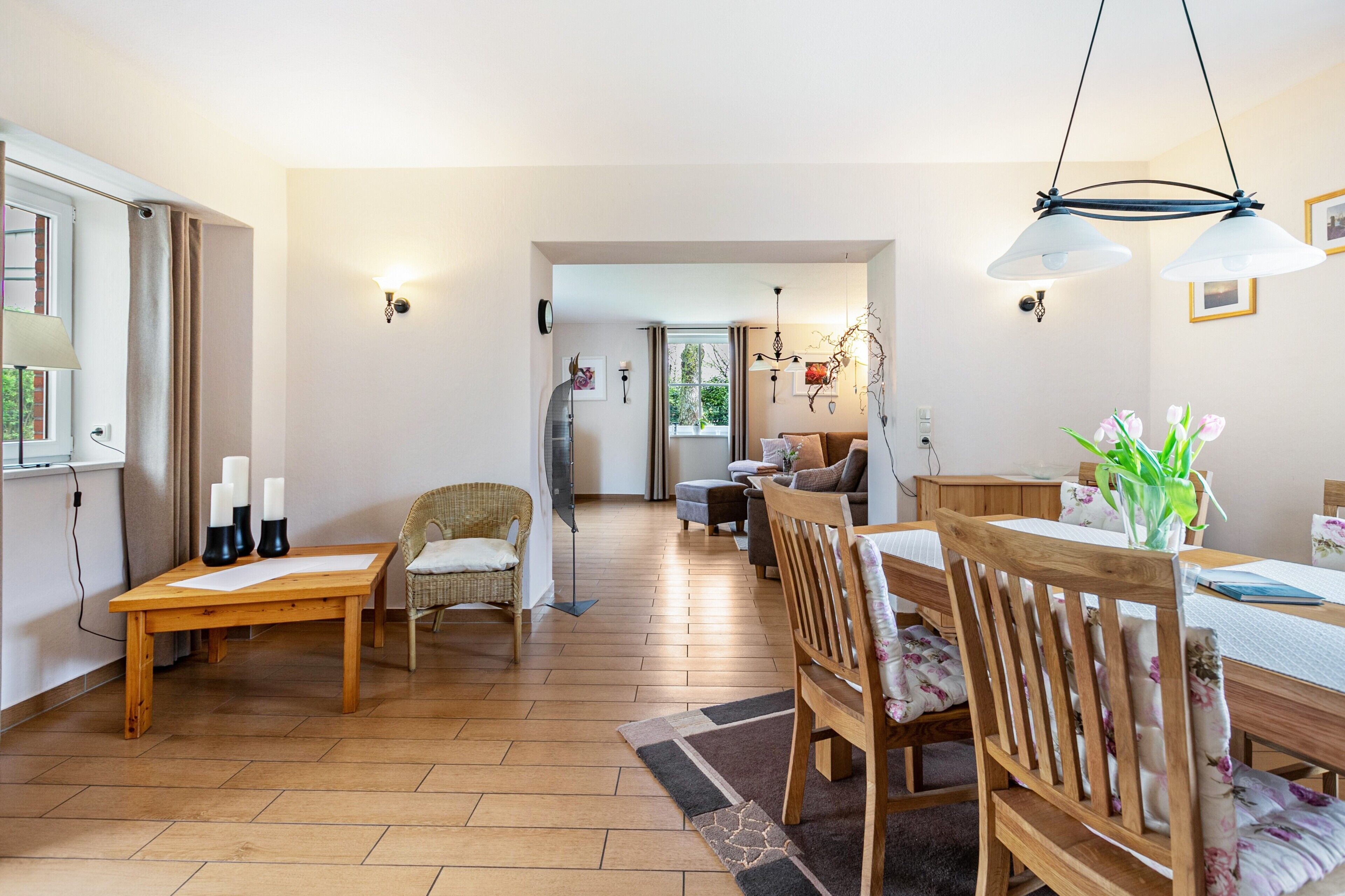 A spacious living area with a wooden dining table, chairs, and a sofa.
