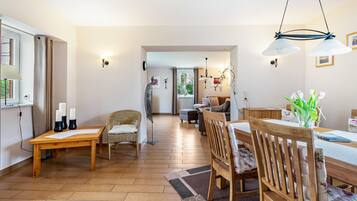 A spacious living area with a wooden dining table, chairs, and a sofa.