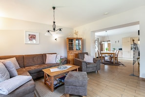 Un salon comprenant un canapé, des fauteuils, une table basse et un meuble.