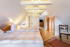 Une chambre avec deux lits, une chaise en bois, une armoire en bois et une petite table avec une lampe.