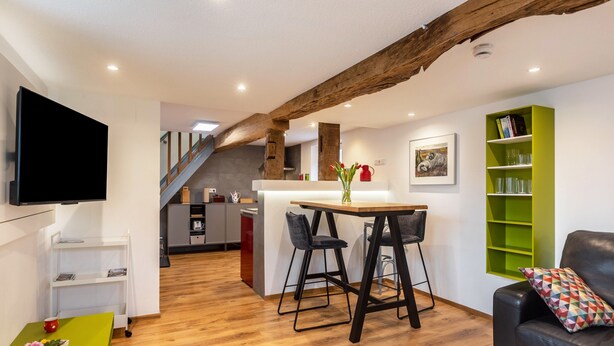 Een moderne woonruimte met keuken, eethoek en zithoek.