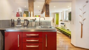 Een moderne keuken met een centraal eiland, roestvrijstalen apparatuur en rode kastjes.