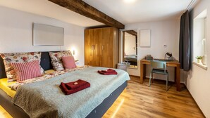 Een slaapkamer met een bed, een houten garderobe, een bureau en een stoel.