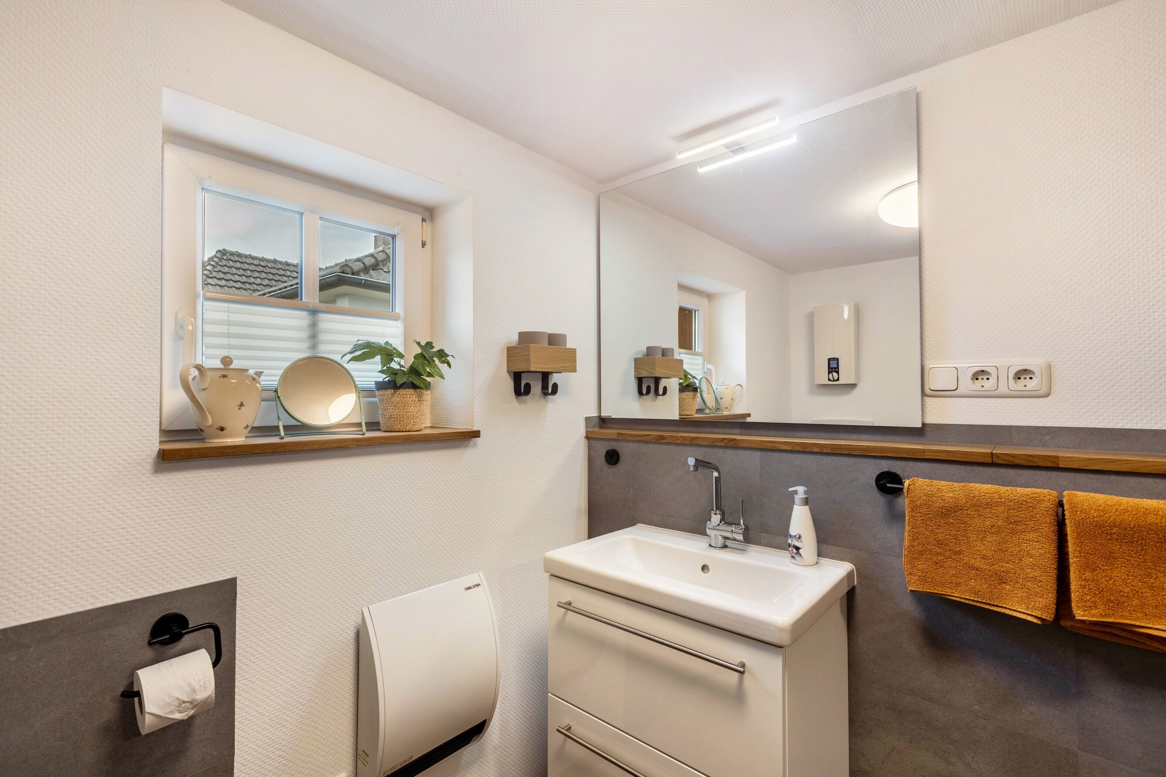 A bathroom with a sink, mirror, towel rack, and a window with a view.