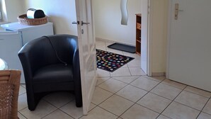 Ein Zimmer mit einem schwarzen Ledersessel, einer weißen Tür, einem wandmontierten Spiegel, einer gepunkteten Matte und einem Korbwäscher auf einem weißen Schrank.