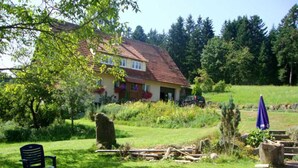 A house with a red roof, surrounded by greenery and a garden. - Apartment 'Ferienwohnung Äckerbartle, 55qm' with Shared Garden, Balcony and Wi-Fi (Wolfach)