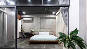 Ein modernes Schlafzimmer mit einem großen Bett, einem Schreibtisch und einer Topfpflanze.