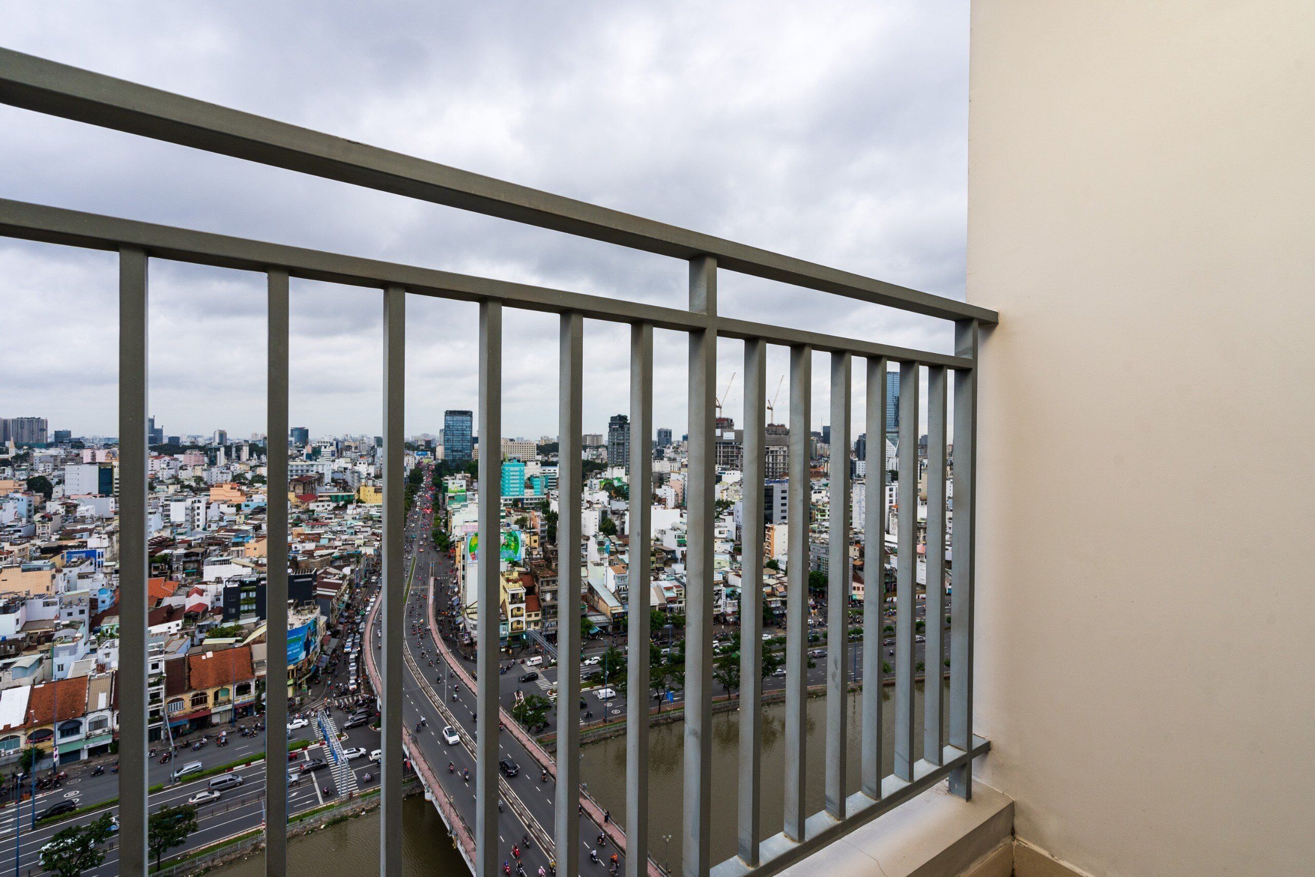 A cityscape viewed from a balcony with a metal railing.