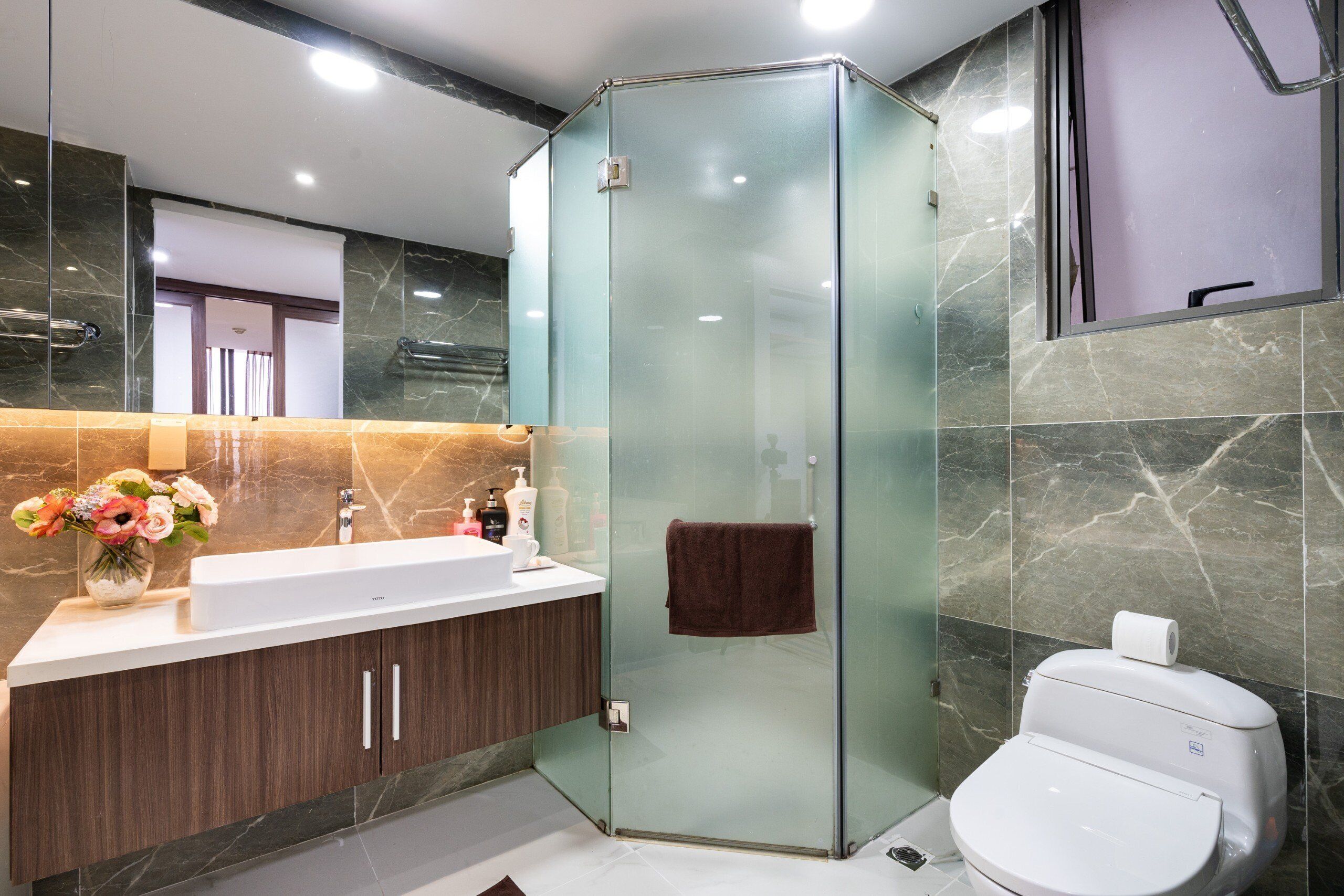 Ein modernes Badezimmer mit einer Glasdusche, einem weißen Waschbecken und einer Toilette.
