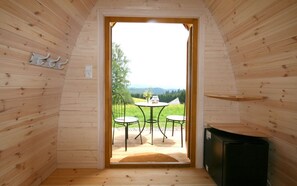 Interior de madera con una puerta que da a un espacio exterior con dos sillas y una mesa.
