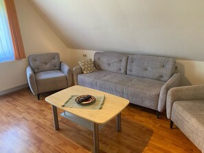 A living room with a sofa, armchairs, a coffee table, and a radiator. - Apartment 'Ferienwohnung Flößerhannes, 75qm' with Private Terrace, Shared Garden and Wi-Fi (Wolfach)