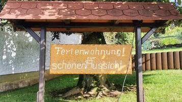 Una pèrgola amb un cartell que diu 'Ferienwohnung! zur schönen Aussicht' davant d'un arbre.