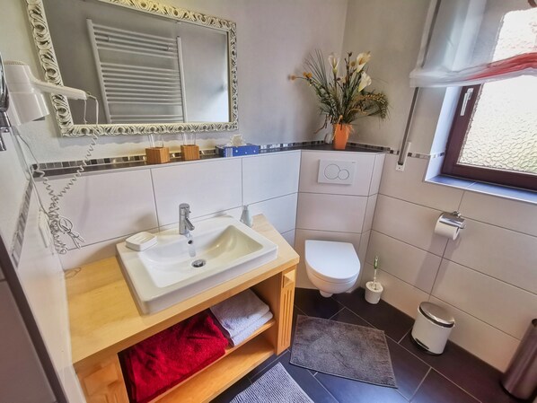 Un baño con lavamanos, inodoro y espejo.