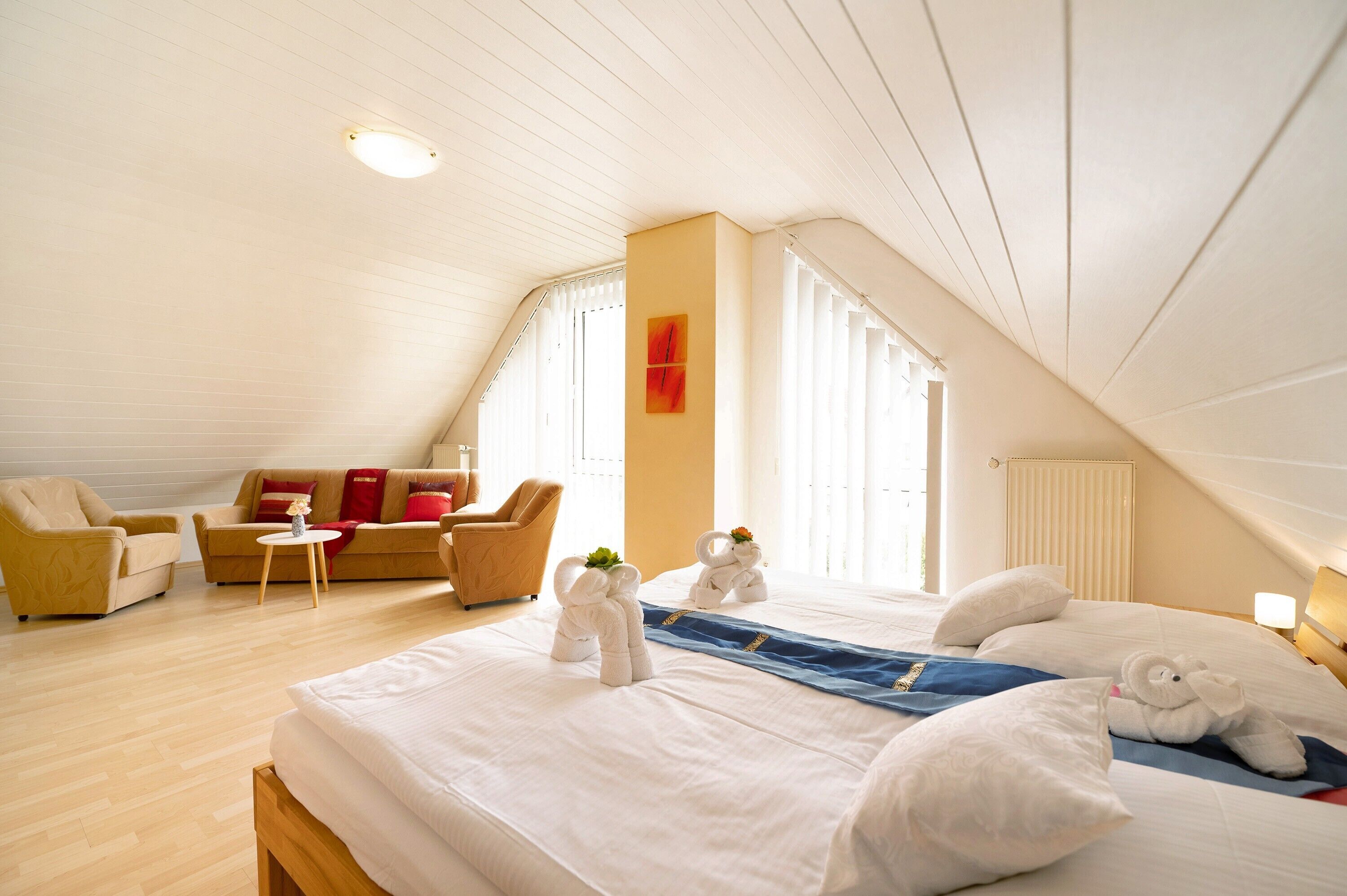 Una habitación de hotel con una cama grande, un sofá, una mesita y una ventana con persianas.