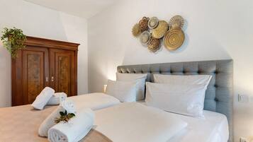 A hotel room with a large bed, a wooden wardrobe, and decorative wall art.