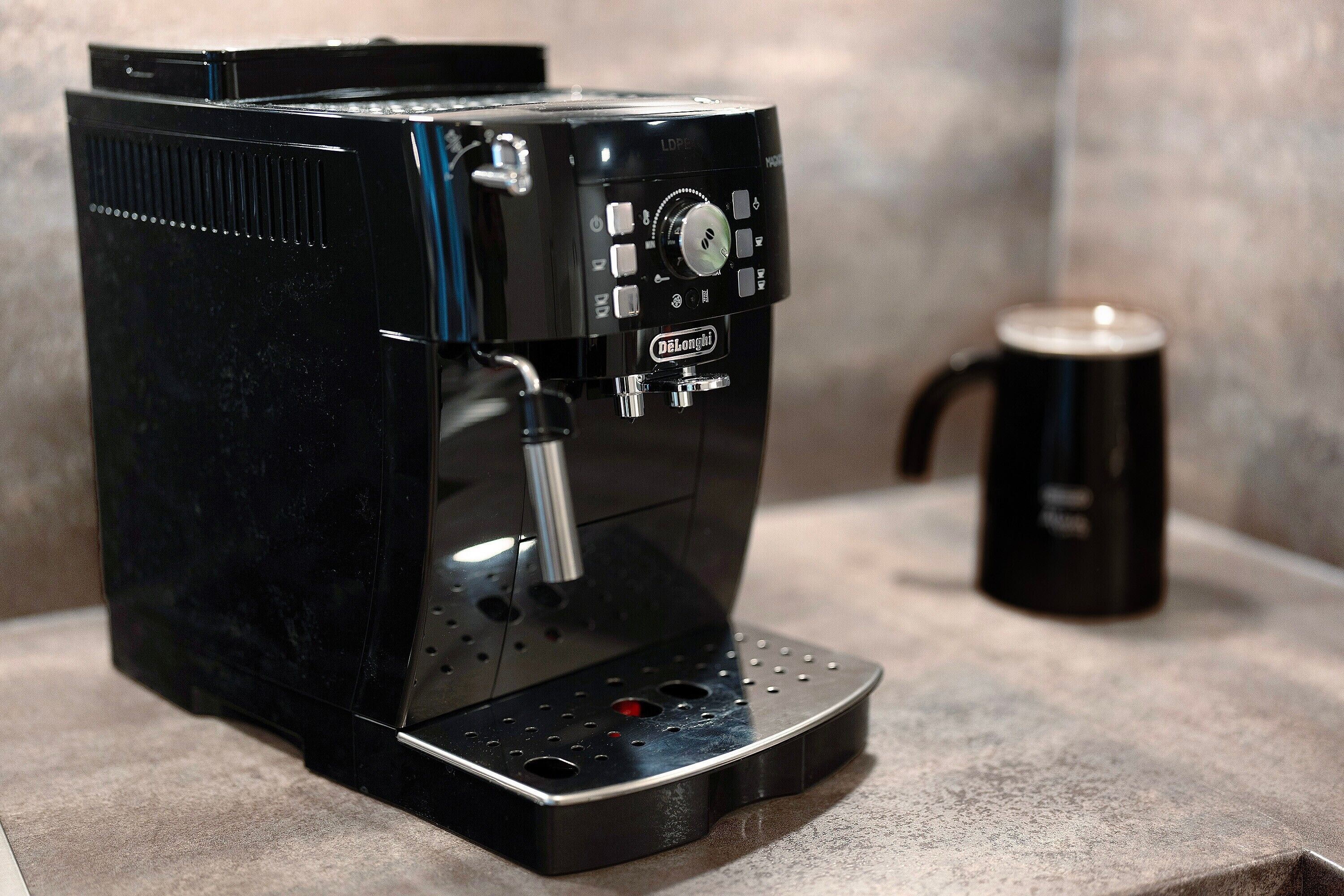 Een zwarte koffiemachine met een bedieningspaneel, een opvangbak en een koffiemok op een aanrecht.