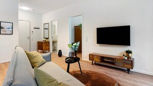A modern living room with a sofa, a TV, a wooden cabinet, and a plant.