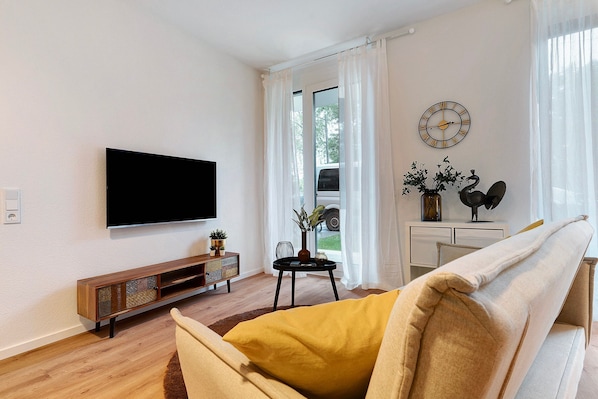 A living room with a flat-screen TV, a sofa, a coffee table, and a sideboard.
