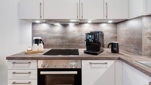 A kitchen with white cabinets, a stove, an oven, and a coffee maker.